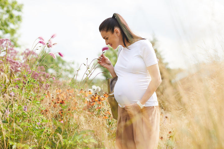 Pregnant woman smelling some flowers and thinking about which prenatal multivitamin is best for her baby